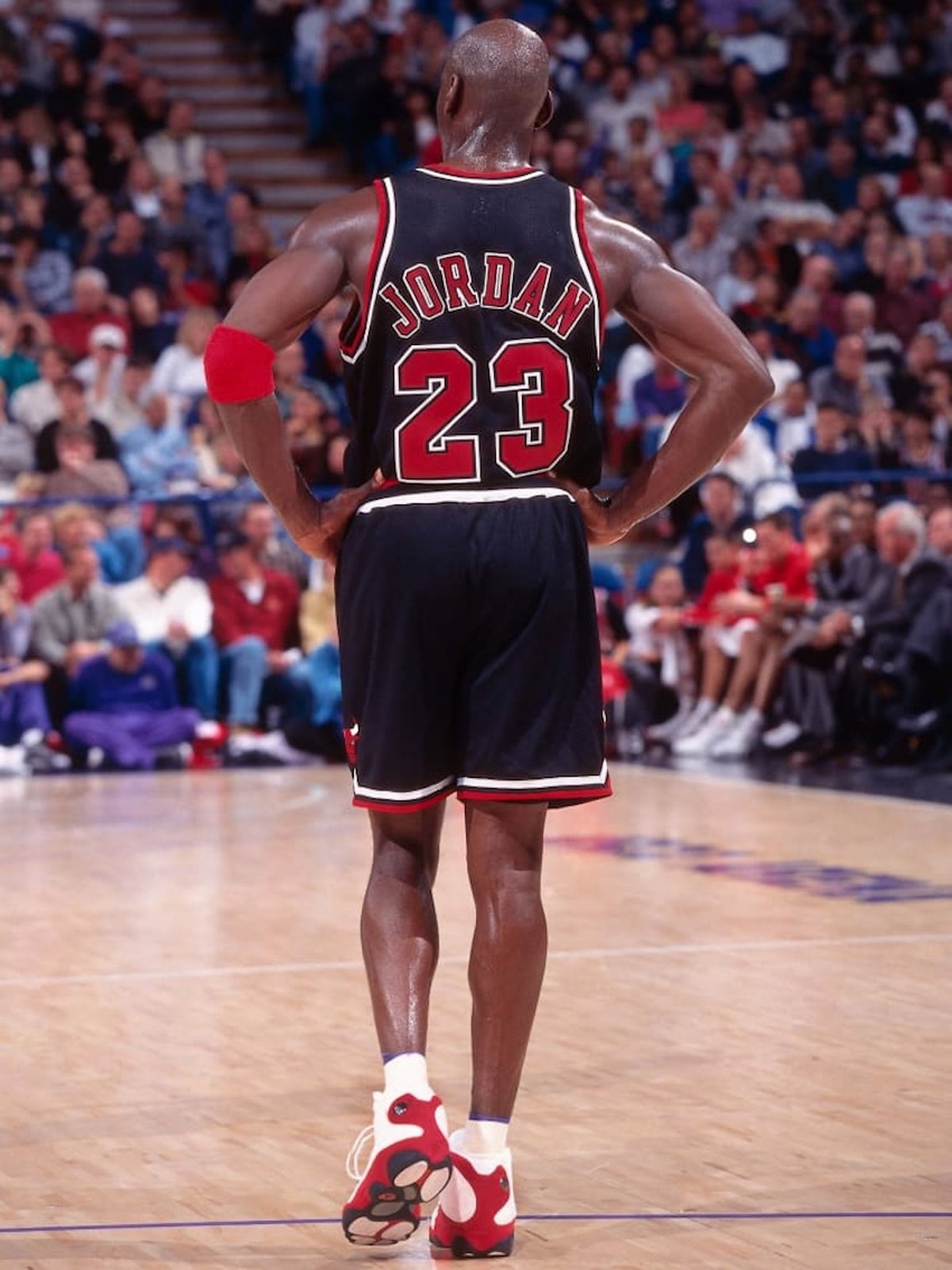 Rear view of Michael Jordan in a black Bulls #23 uniform, showing the outsole and heel of the Jordan 13 “Chicago/True Red” on court